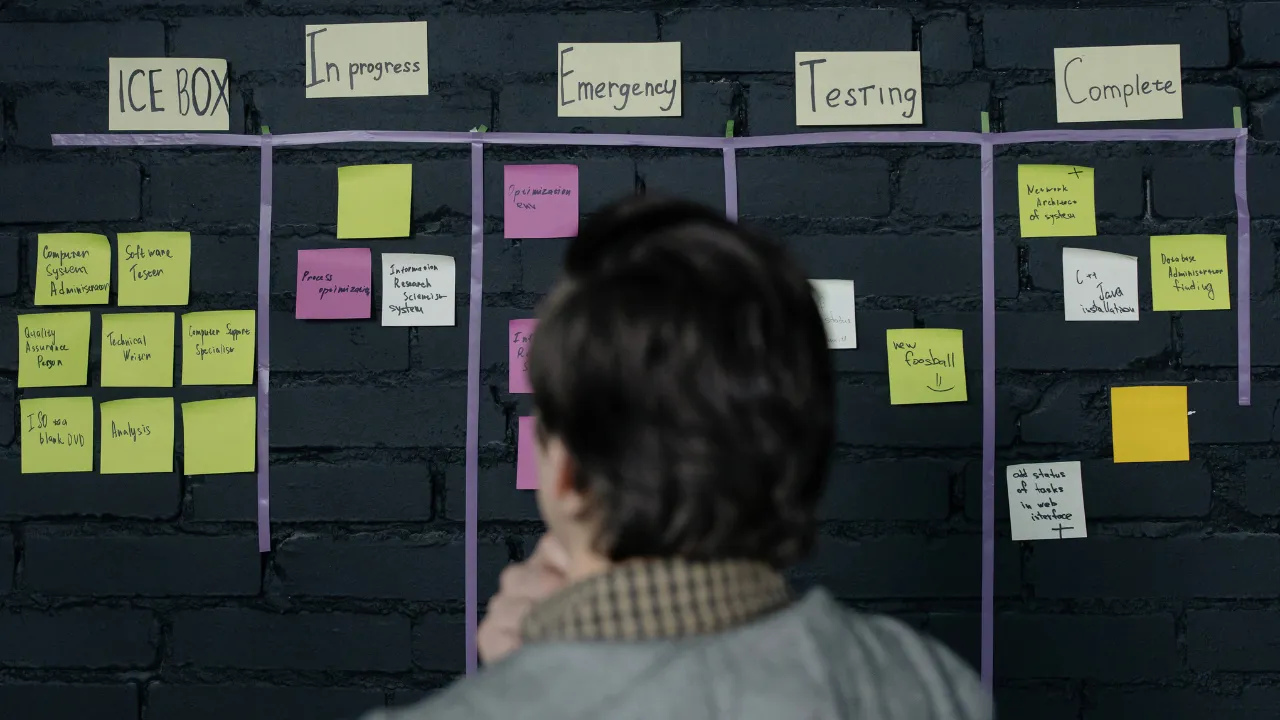 Illustration d'un chef de projet ou d'un développeur utilisant la méthode agile. Un homme est face à un tableau de post-it pour organiser les tâches d'un projet web, symbolisant la planification par sprints et l'approche collaborative.